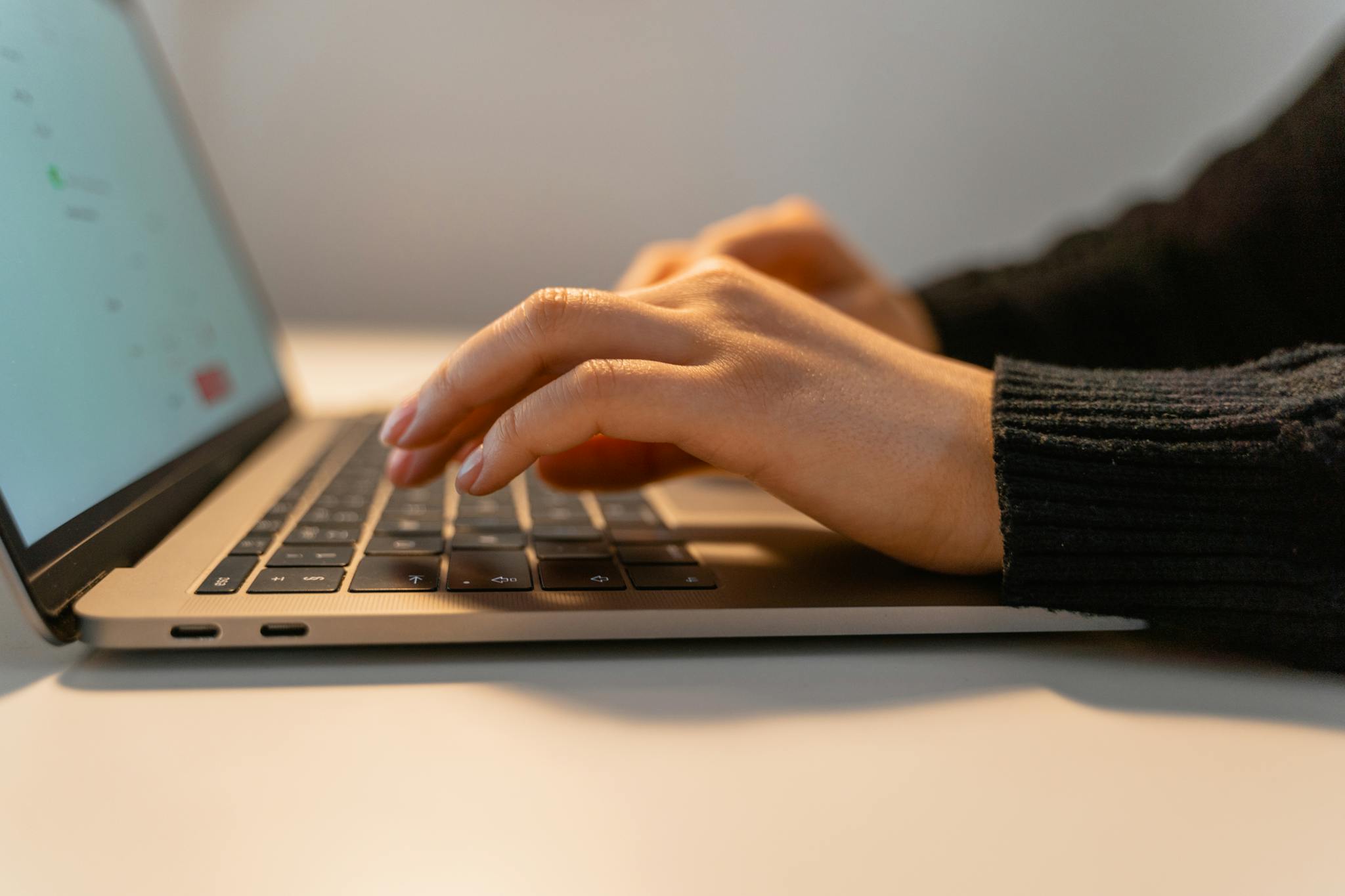 Close-up view of hands typing on a laptop keyboard, illustrating the concept of remote work and technology.