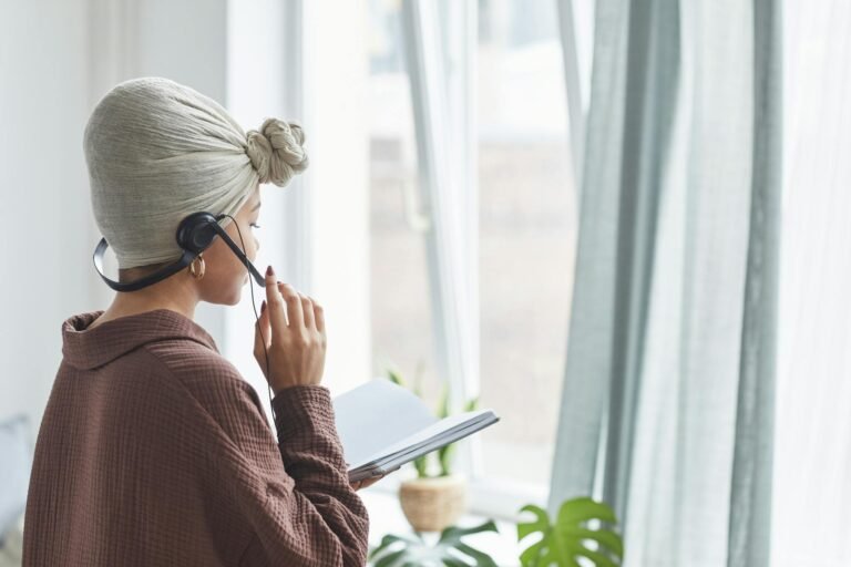 Side view of a woman in a turban using a headset while reading at home.